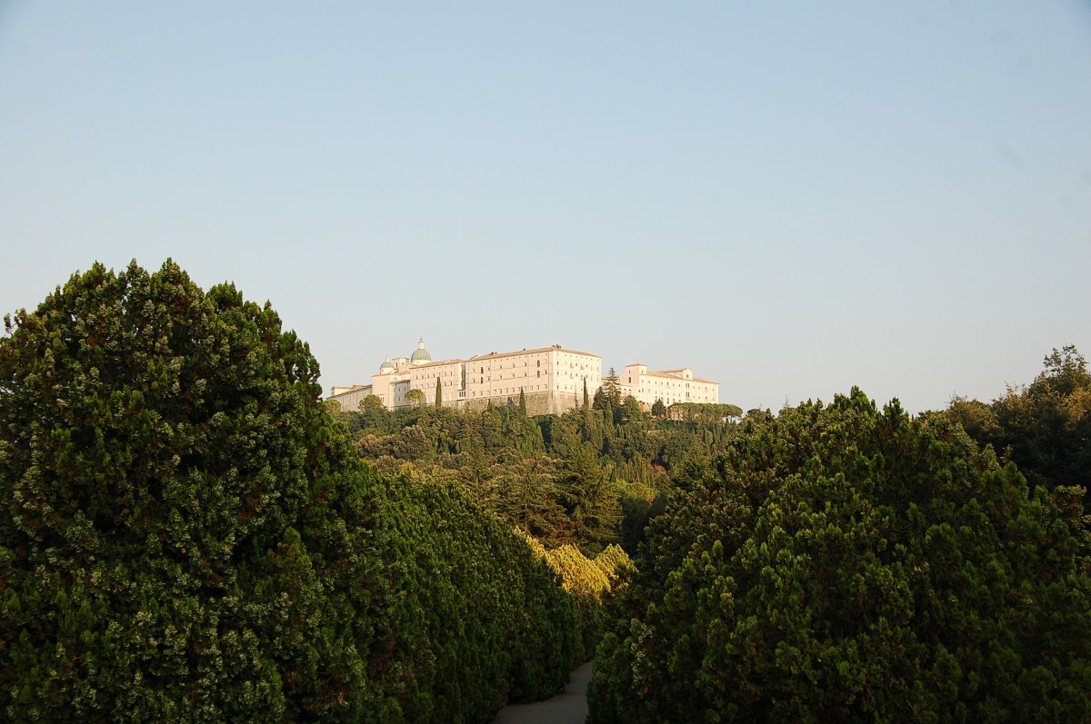Polish War Cemetery at Monte Cassino, with rows of white headstones on the terraced slope below the abbey