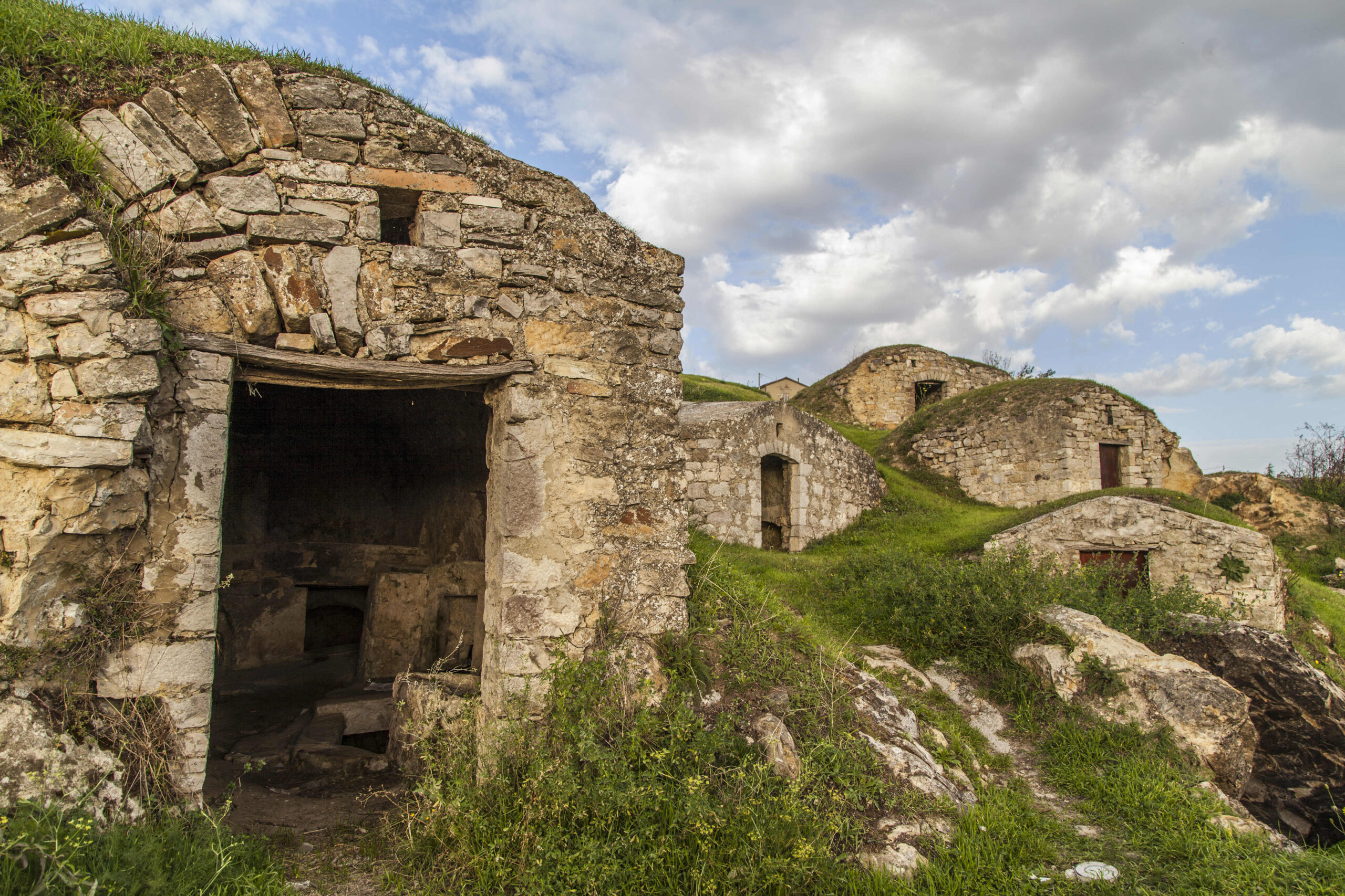 Close detail of two adjoining palmenti at Pietragalla showing the stone façades, low entrance doors and overhead ventilation slits