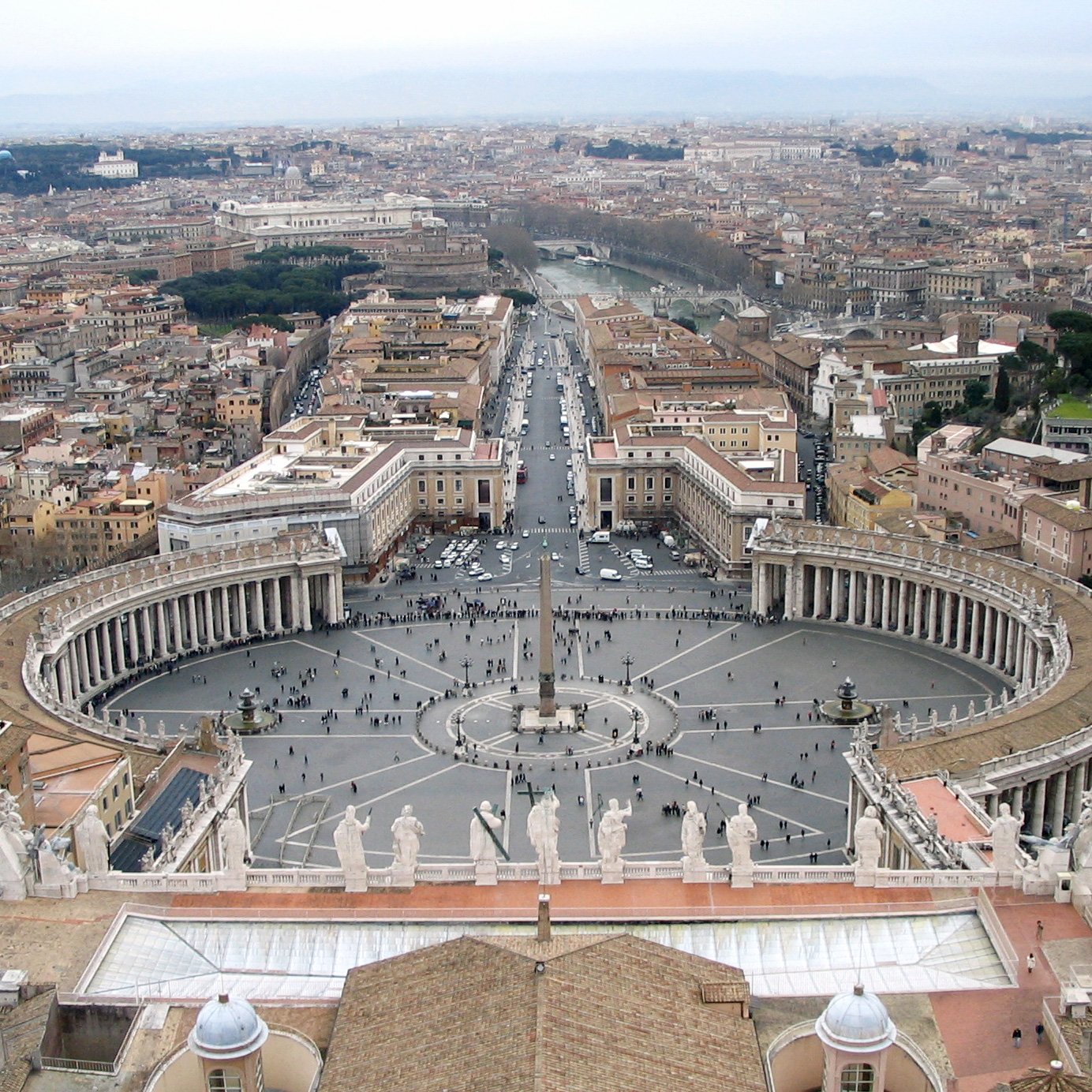 Aerial view of the elliptical piazza from the basilica dome, showing the four-row Tuscan colonnade, the central obelisk and the two fountains