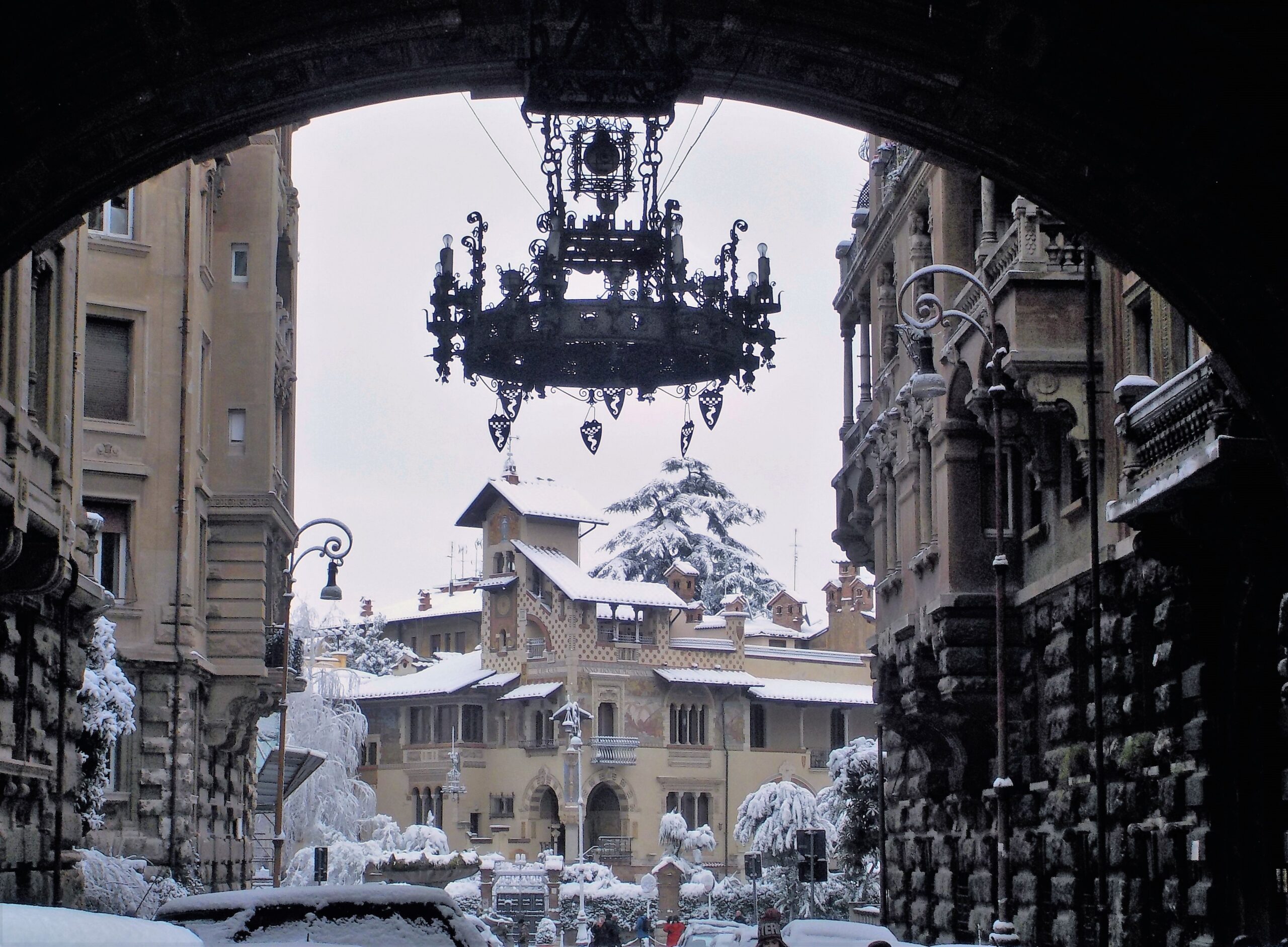 Wrought-iron chandelier hanging under the monumental entrance arch of the Coppedè District on Via Tagliamento, Rome