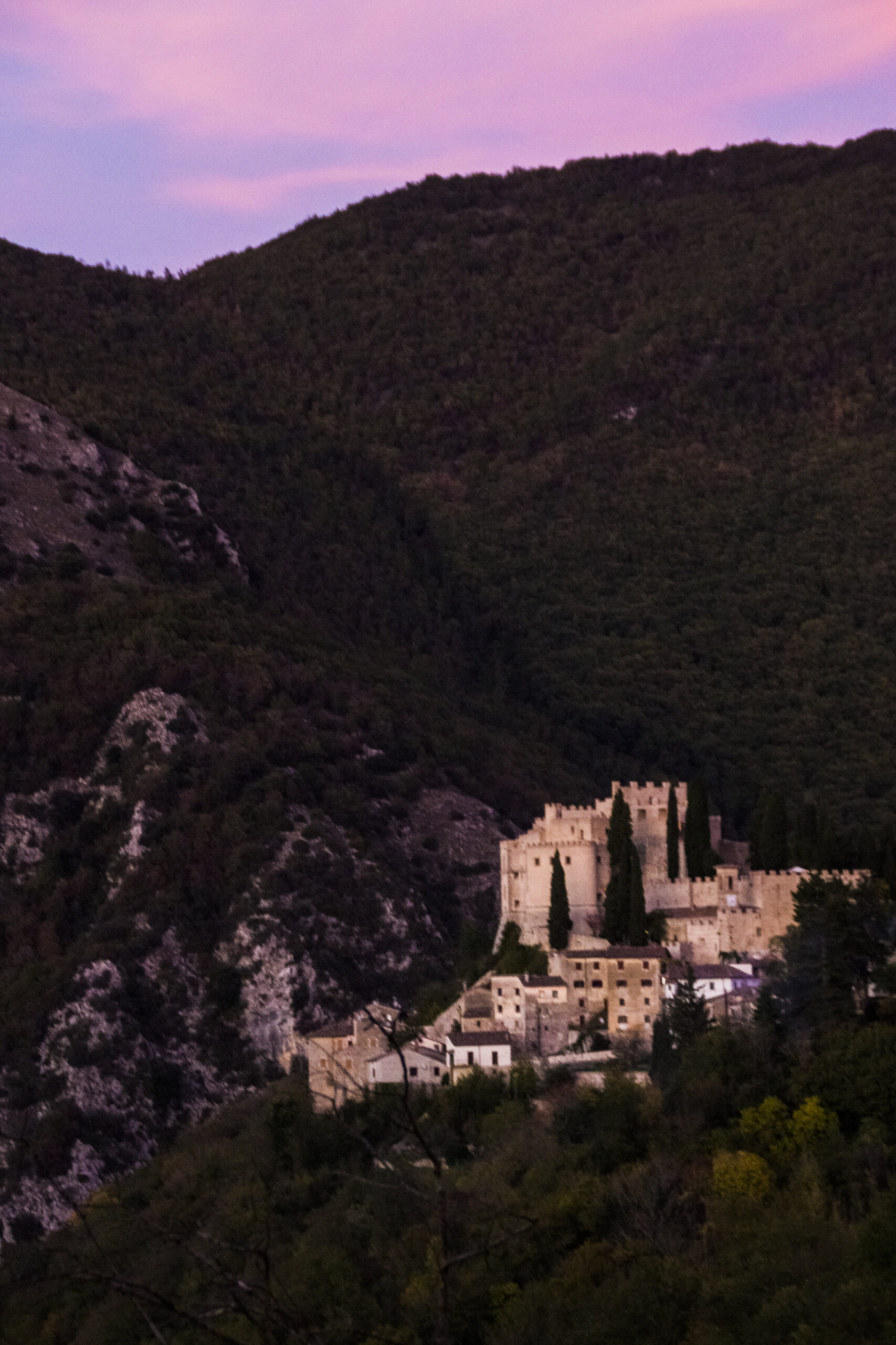 The Castello di Rocca Sinibalda at dusk, its bastions silhouetted against an evening sky