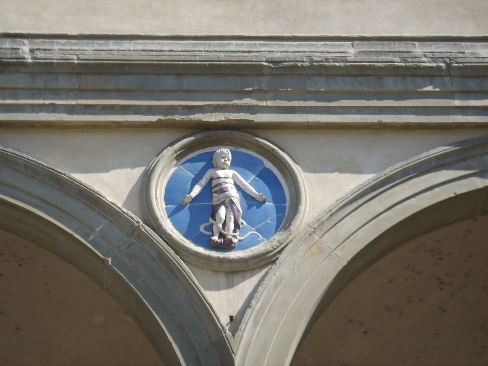 Glazed terracotta medallion by Andrea della Robbia showing a swaddled infant against a blue ground
