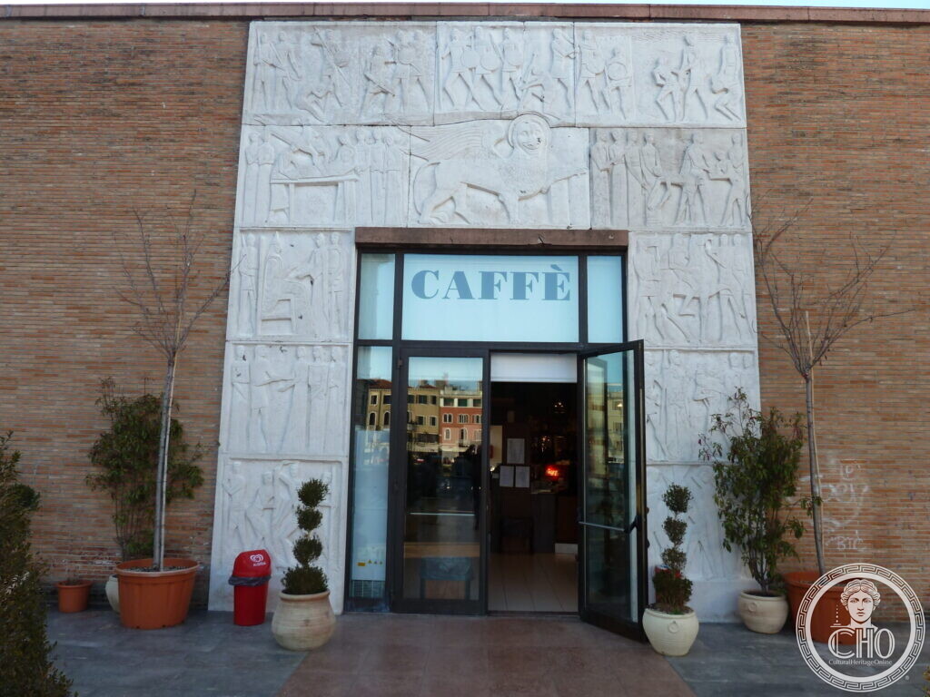 A glazed doorway framed by white stone panels carved with figures in low relief, set into a brick wall