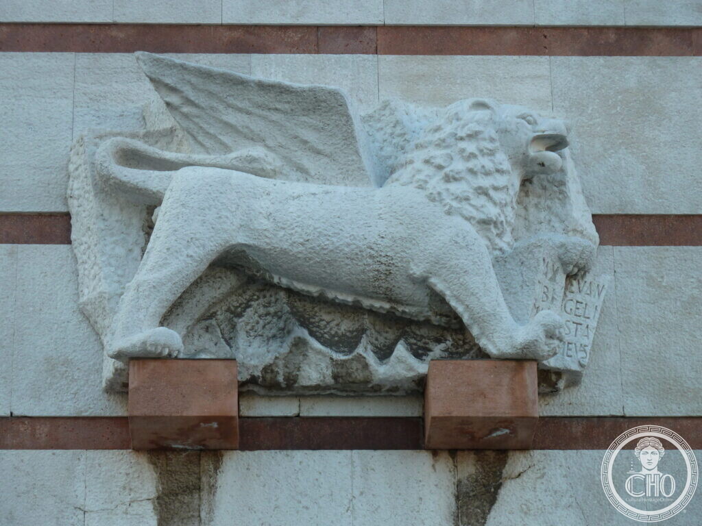 A stone relief of the winged lion of Saint Mark set into a pale stone wall banded with red