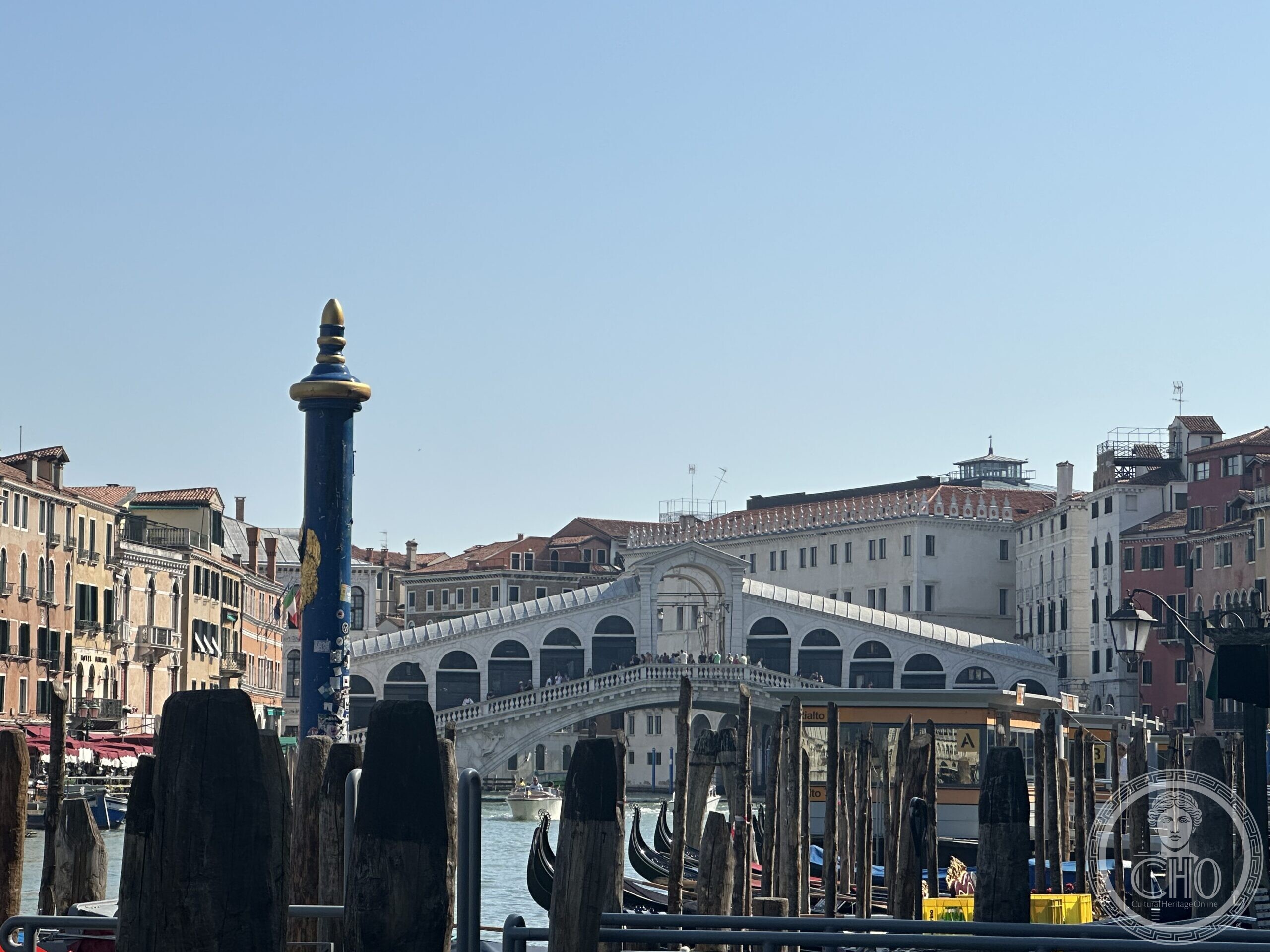 The Rialto Bridge seen from the Grand Canal past gondola prows and mooring poles