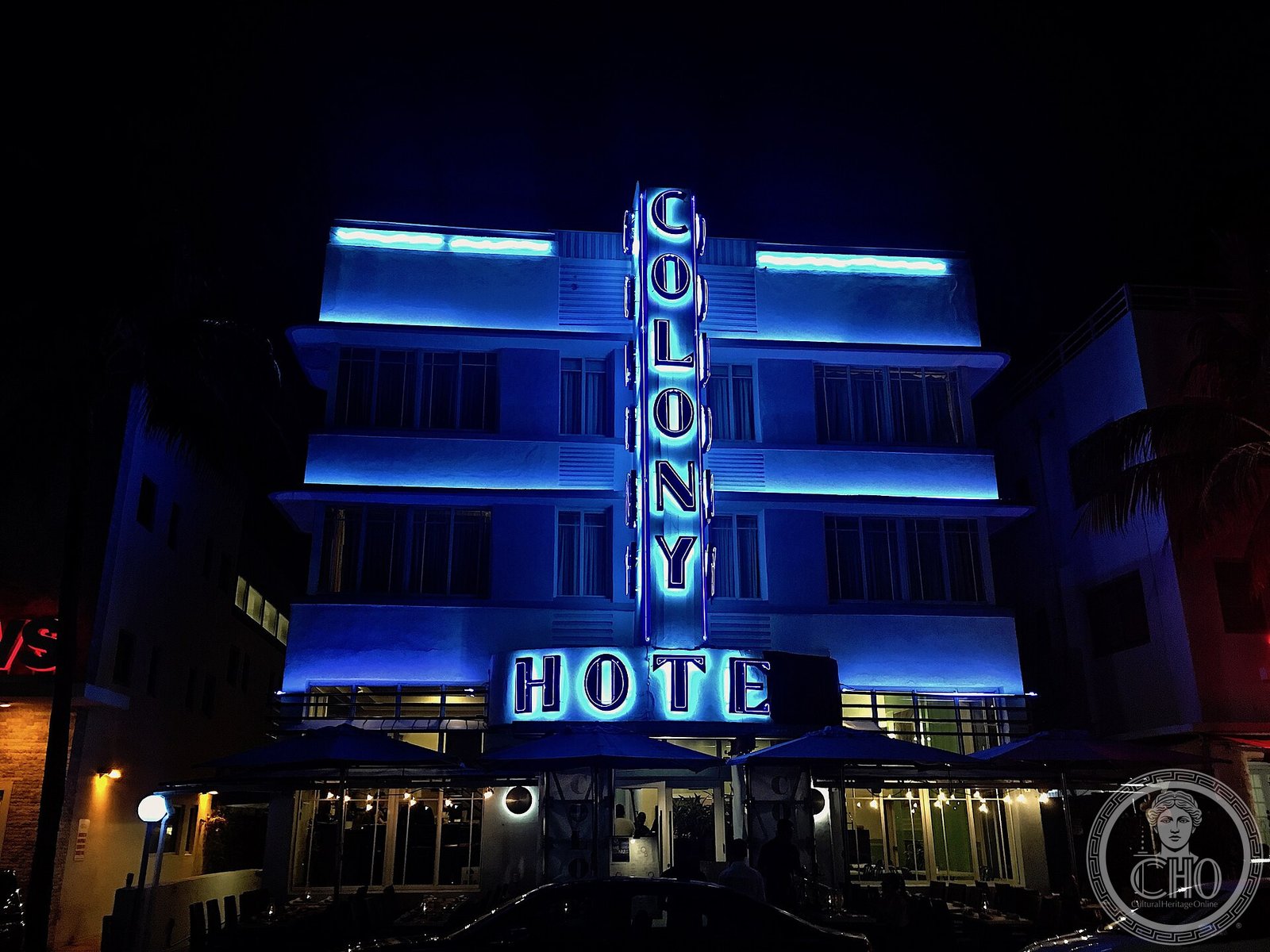 The Colony Hotel facade glowing in blue neon at night on Ocean Drive, Miami Beach