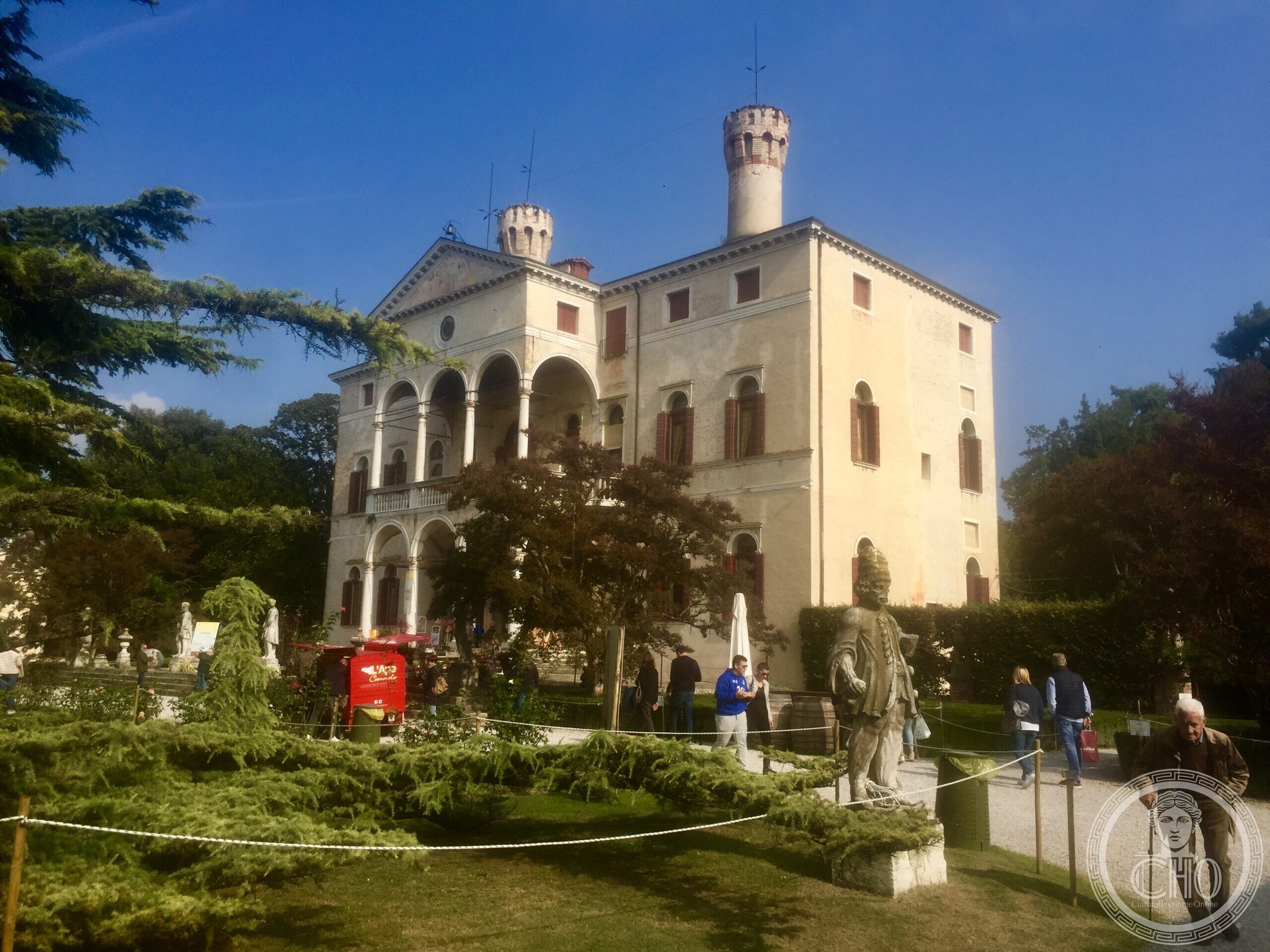 Full view of the Renaissance villa and towers of Roncade Castle, with a garden statue in front