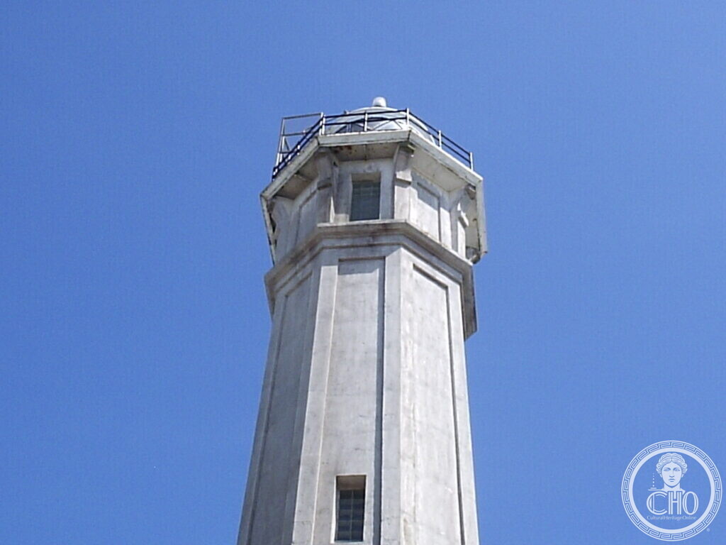White octagonal concrete lighthouse tower against a deep blue sky