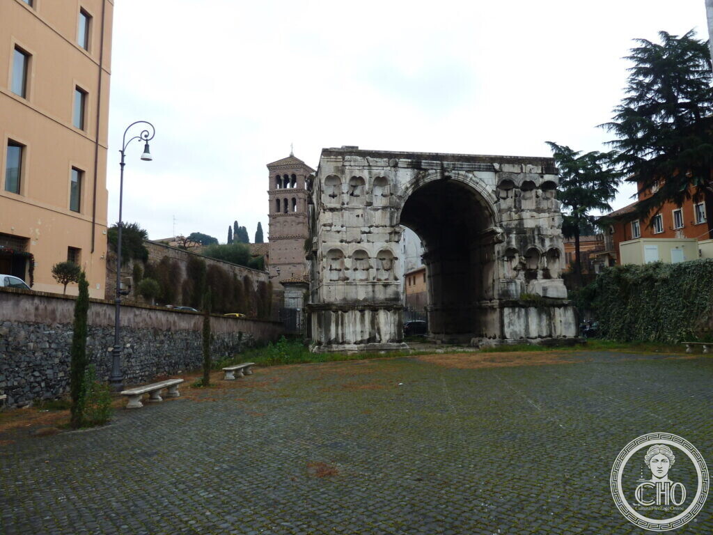 The four-faced arch seen from the side, a brick Romanesque bell tower rising behind it