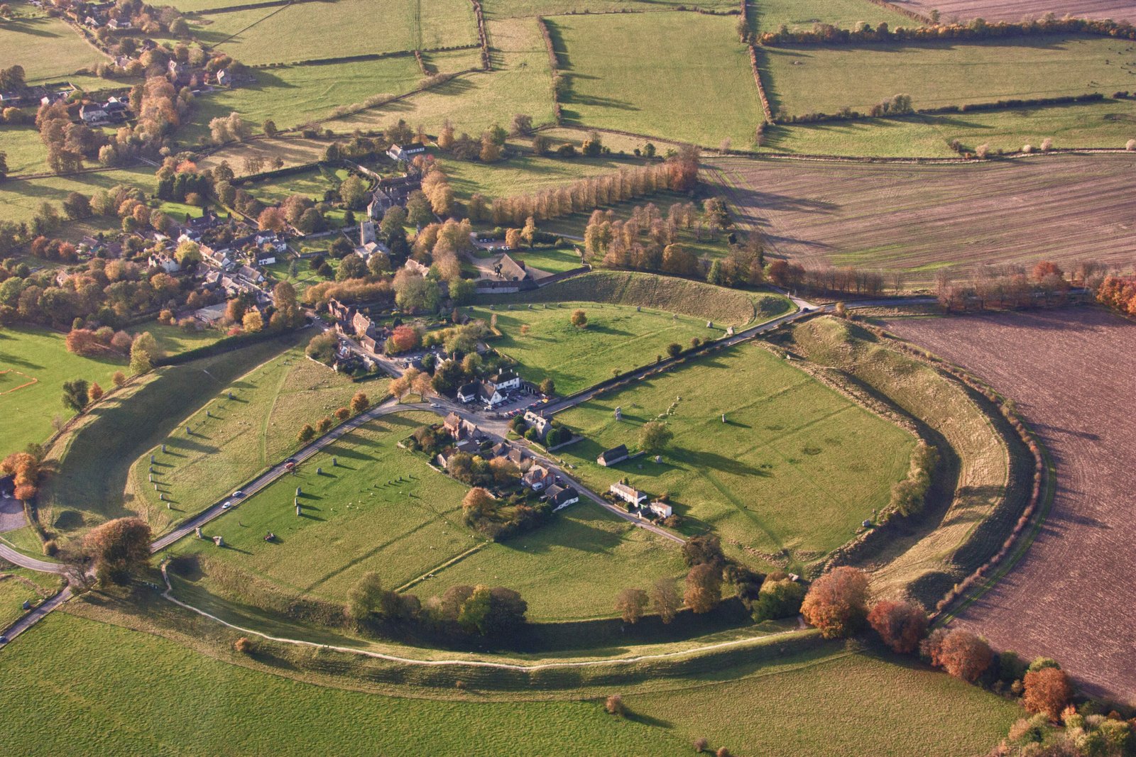 Standing stones of Avebury stone circle with village buildings visible between the megaliths, Wiltshire, England Standing stones of Avebury stone circle with village buildings visible between the megaliths, Wiltshire, England