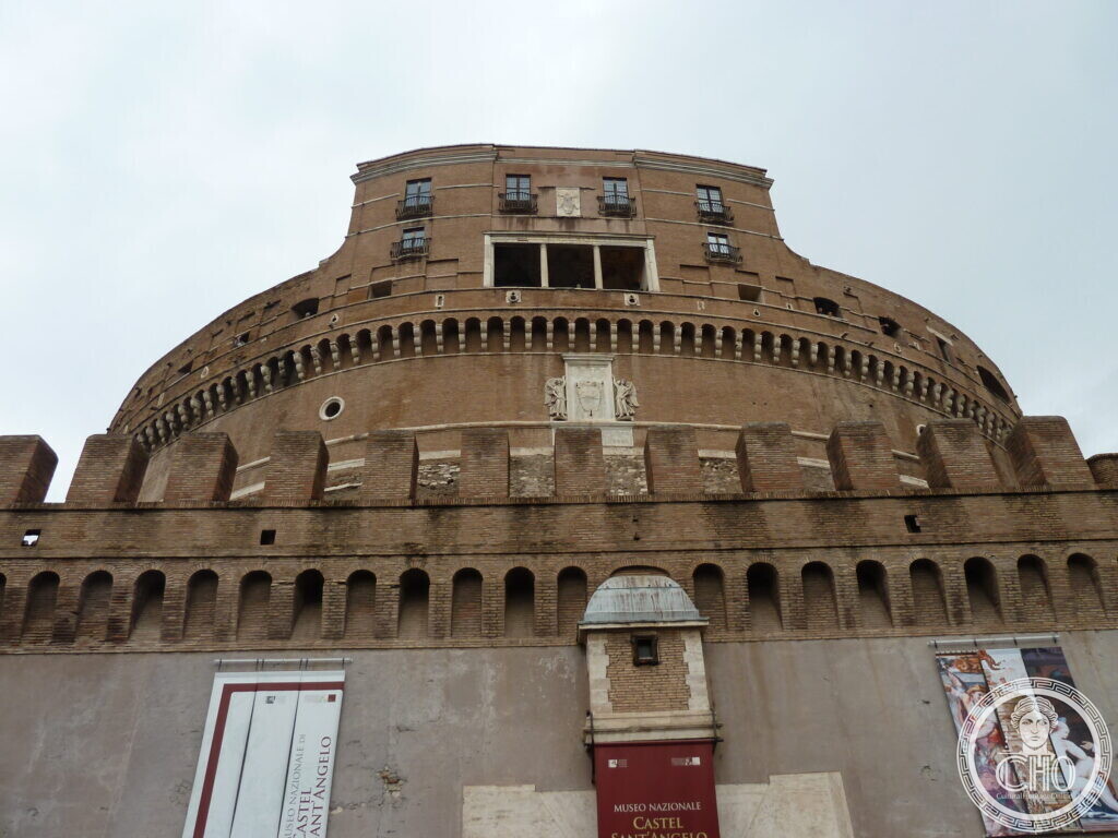 Round brick castle with a square entrance block, crenellated outer walls and museum signs by the door