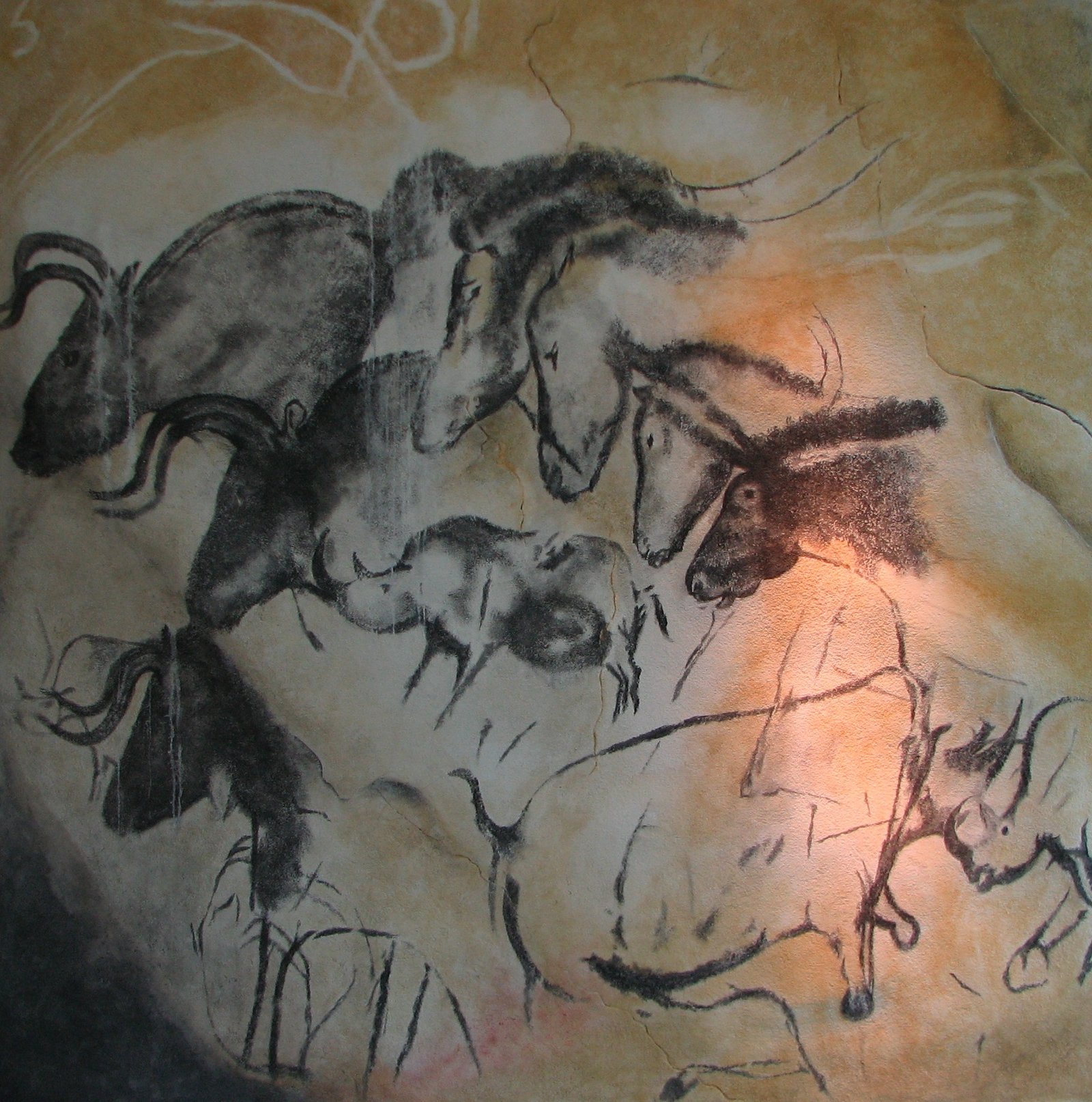 Replica of Chauvet Cave paintings showing charging rhinoceroses and horses in ochre and charcoal