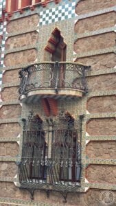 — A wrought-iron balcony set against the banded brick façade.
