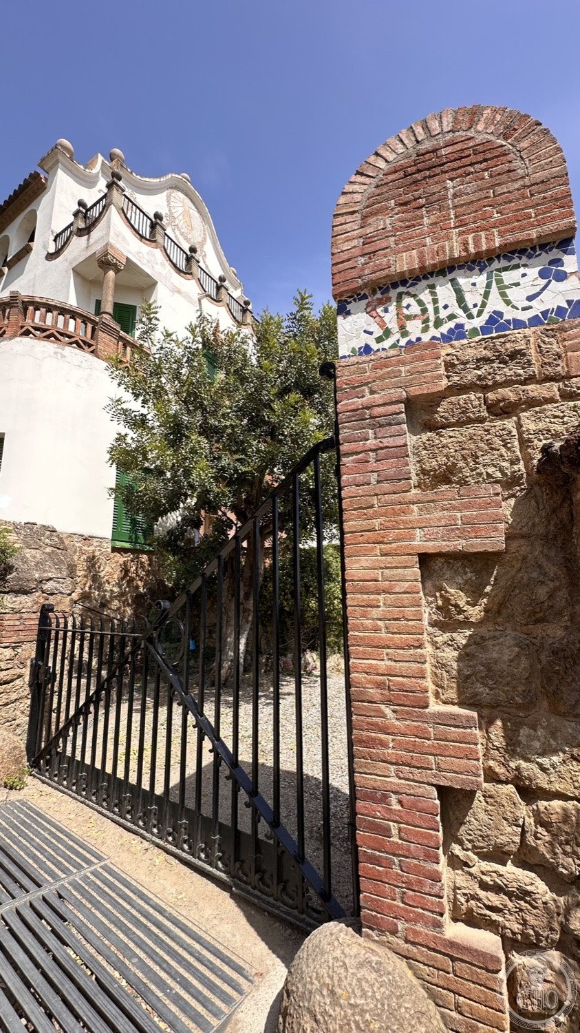 Park Güell — The park gate and the 'Salve' mosaic on its brick pillar.
