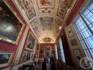 Palatine Gallery — Pitti Palace, red walls, floor-to-ceiling paintings, frescoed vault, Florence