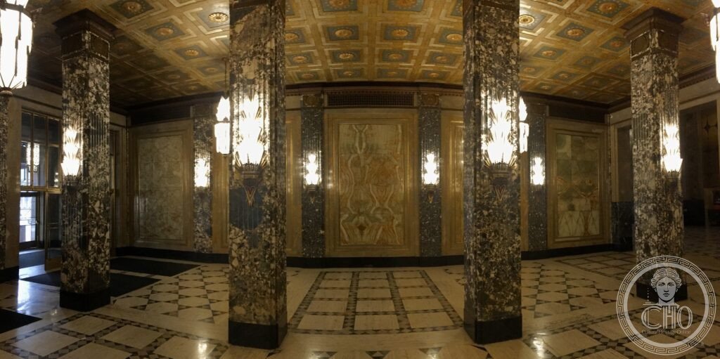 An interior colonnade of glossy marble pillars in a stylized Art Deco design extends inward from the