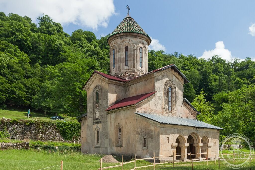A stone medieval church of Gelati Monastery among green hills in western Georgia