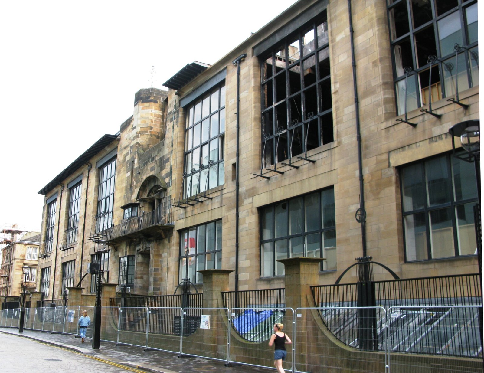 Stone facade of the Glasgow School of Art with tall studio windows and wrought-iron brackets