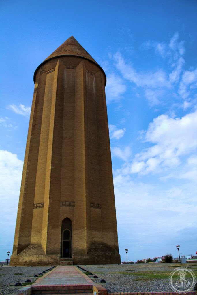 The tall conical brick tomb tower of Gonbad-e Qabus against a blue sky in Iran