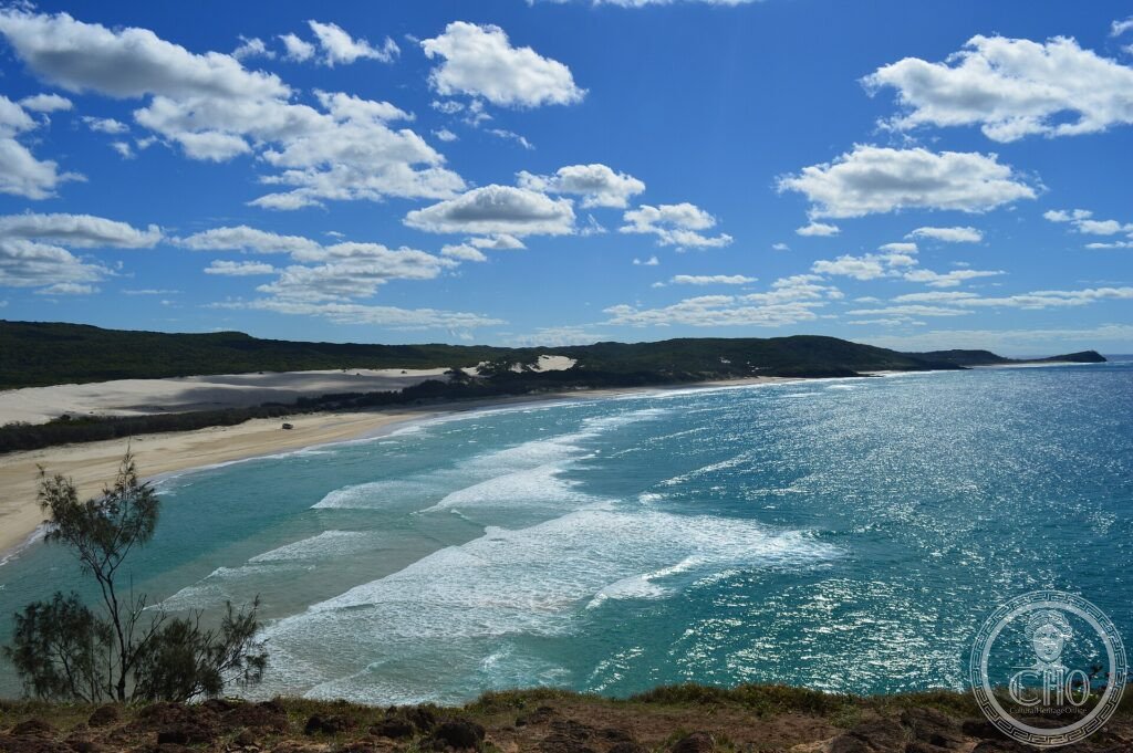 A long sandy surf beach and turquoise sea seen from a vegetated headland on K'gari (Fraser Island)