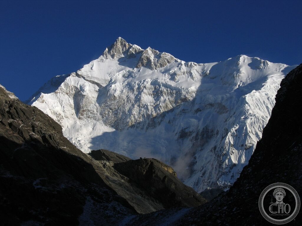 The snow-covered peak of Kangchenjunga rising above dark ridges in Sikkim