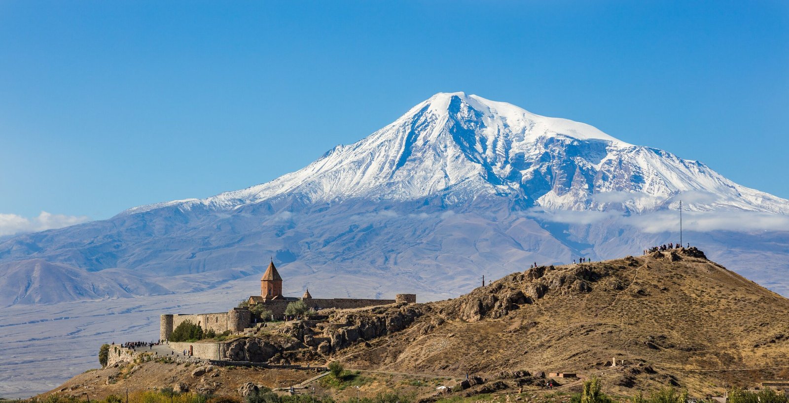Khor Virap monastery on its hillock in the Ararat Valley, with the snow-capped peaks of Greater and Lesser Ararat visible behind, Armenia