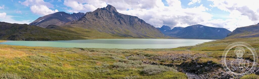 A turquoise mountain lake below rugged peaks and tundra in the Sarek wilderness of Laponia, Sweden