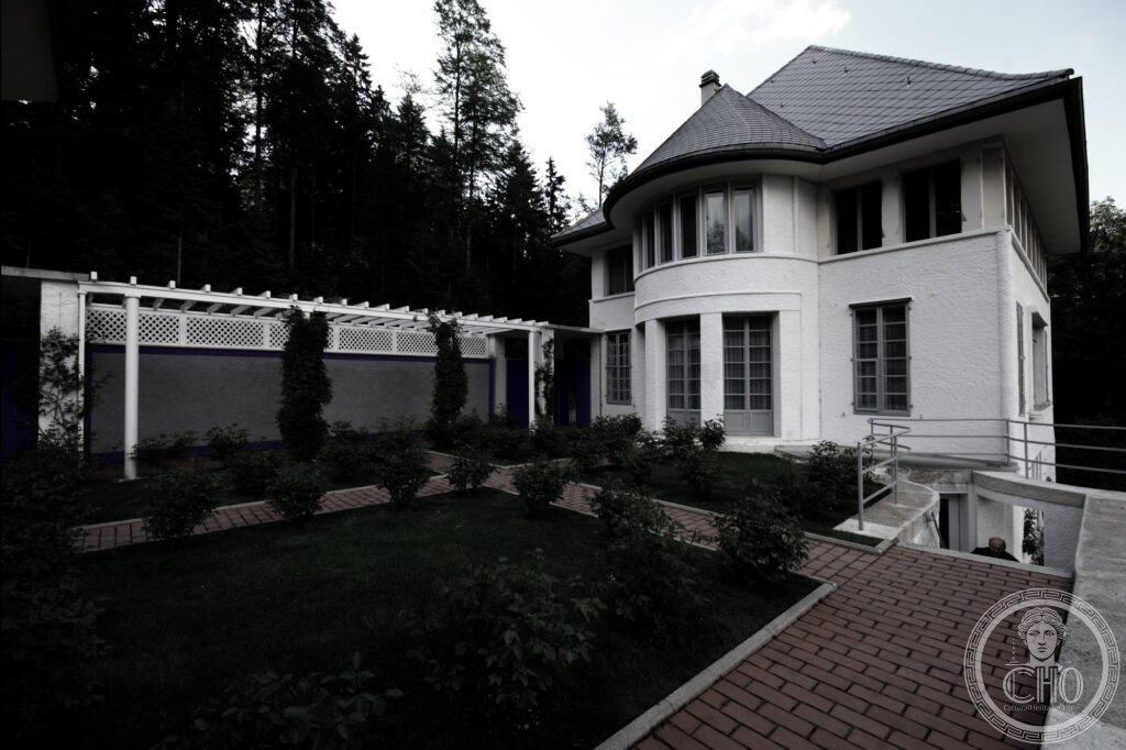White cubic volume of the Maison Blanche framed by pines on Chemin de Pouillerel, La Chaux-de-Fonds