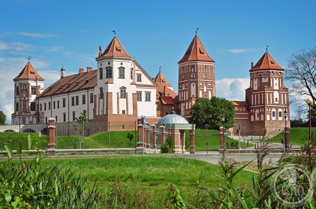 The red-brick towers and white walls of Mir Castle reflected in calm light