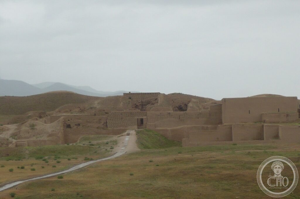 Eroded mud-brick walls and mounds of the Parthian fortress of Nisa on a green plain, Turkmenistan
