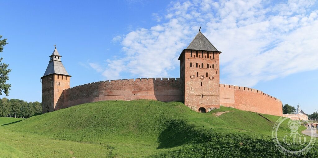 The red-brick walls and towers of the Novgorod Kremlin (Detinets) on a grassy mound