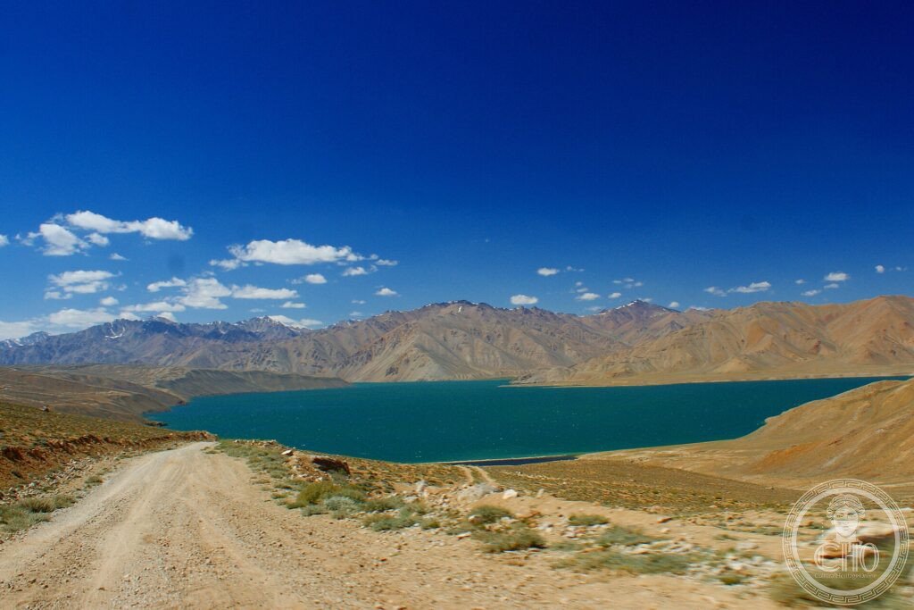 A turquoise high-altitude lake among bare brown Pamir mountains under a deep blue sky, Tajikistan