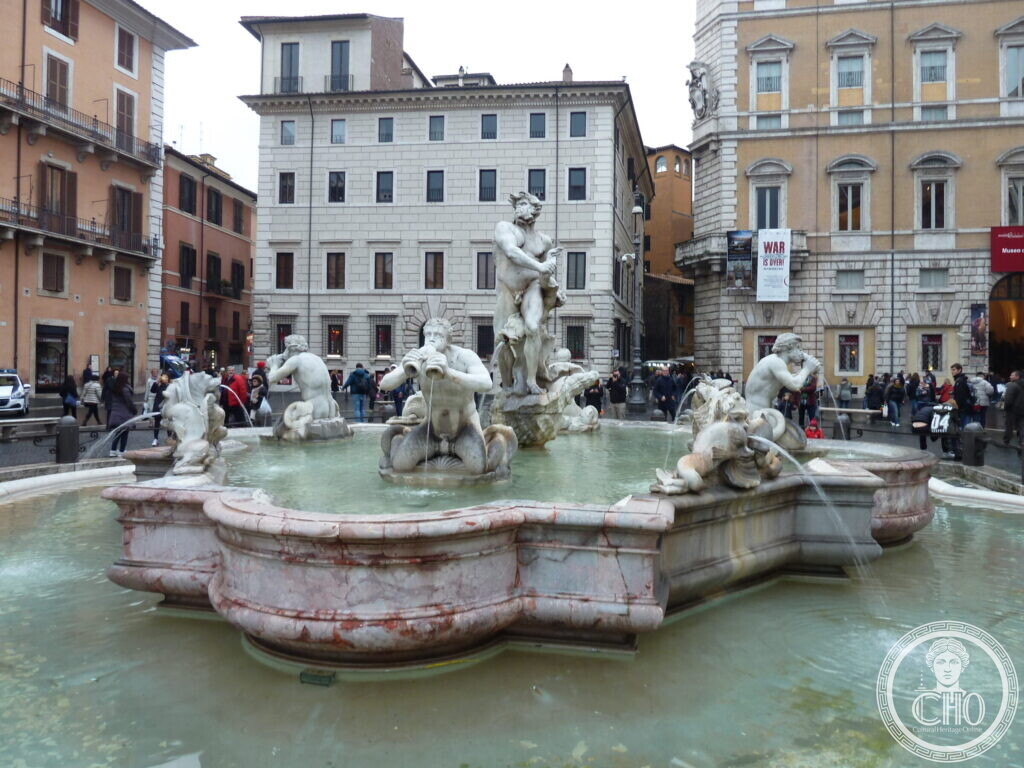 Fountain with a marble figure wrestling a dolphin in the middle of a lobed basin, tritons around him and palaces behind