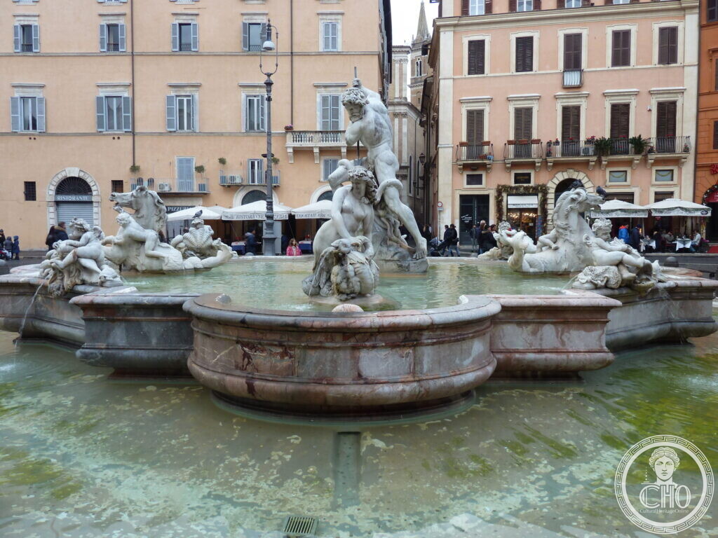 Baroque fountain with a marble statue of Neptune striking an octopus with a trident, surrounded by sea creatures and nereids in a wide basin