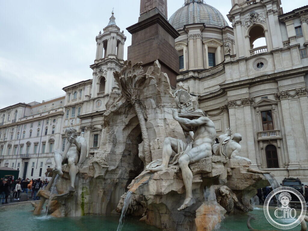 Fountain of rough travertine rock with reclining river gods and an obelisk, the baroque church front with towers and dome behind