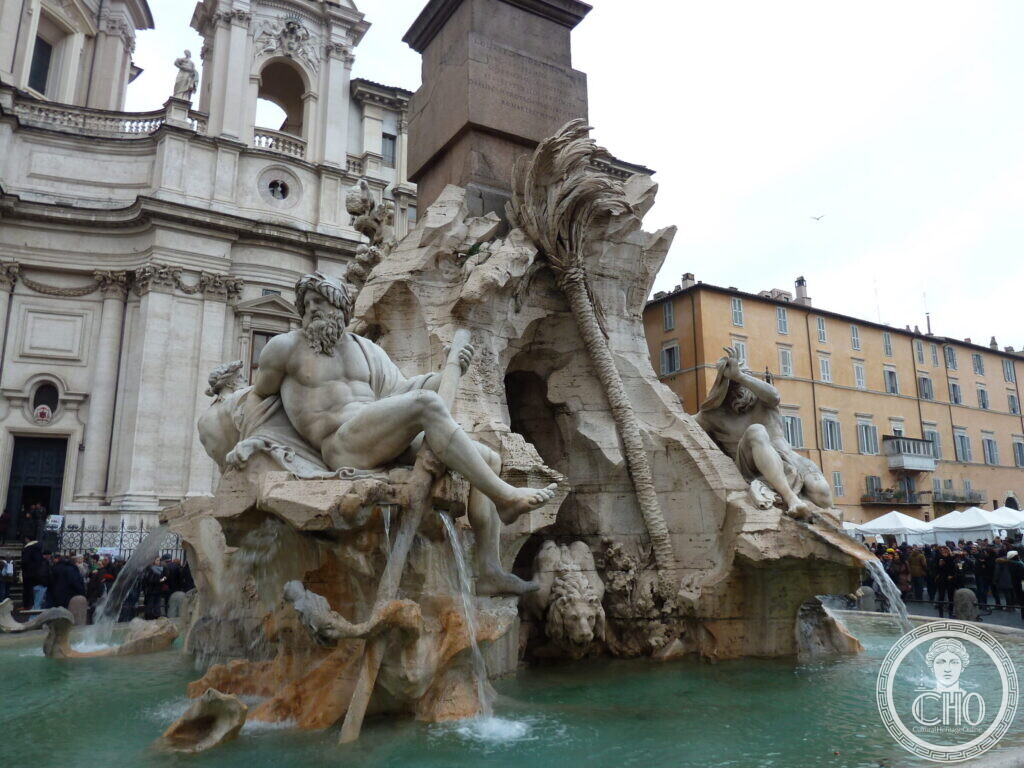 Close view of a reclining marble river god on the travertine rock of the fountain, a carved palm tree and the base of the obelisk above