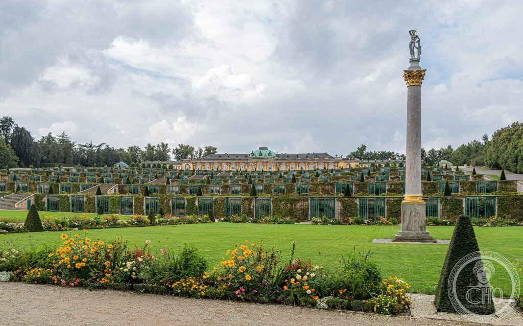 Sanssouci Palace above its terraced vineyard with a statue and gardens in the foreground
