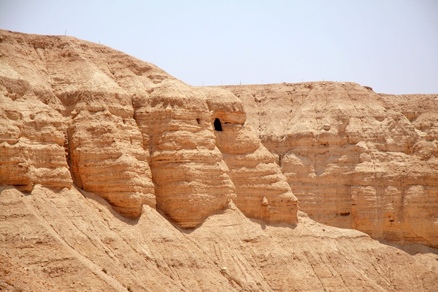 Ruins of the Qumran communal settlement on the Dead Sea shore with the limestone cliffs of Cave 4 visible above