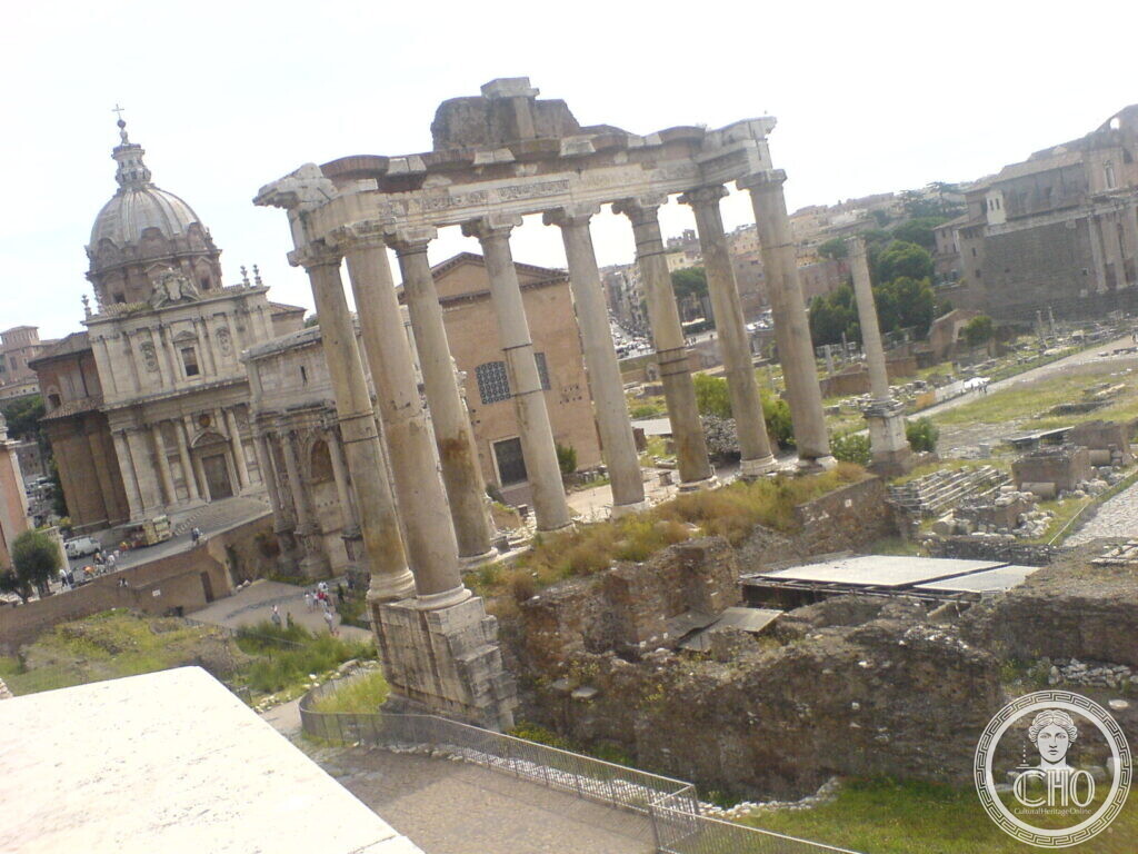 Eight tall grey granite columns with a fragment of entablature standing on a high podium, a baroque church dome to the left