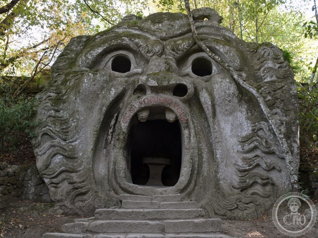Sacro Bosco di Bomarzo, mostro in pietra peperino con bocca spalancata e iscrizione manierista nel bosco sacro, Viterbo