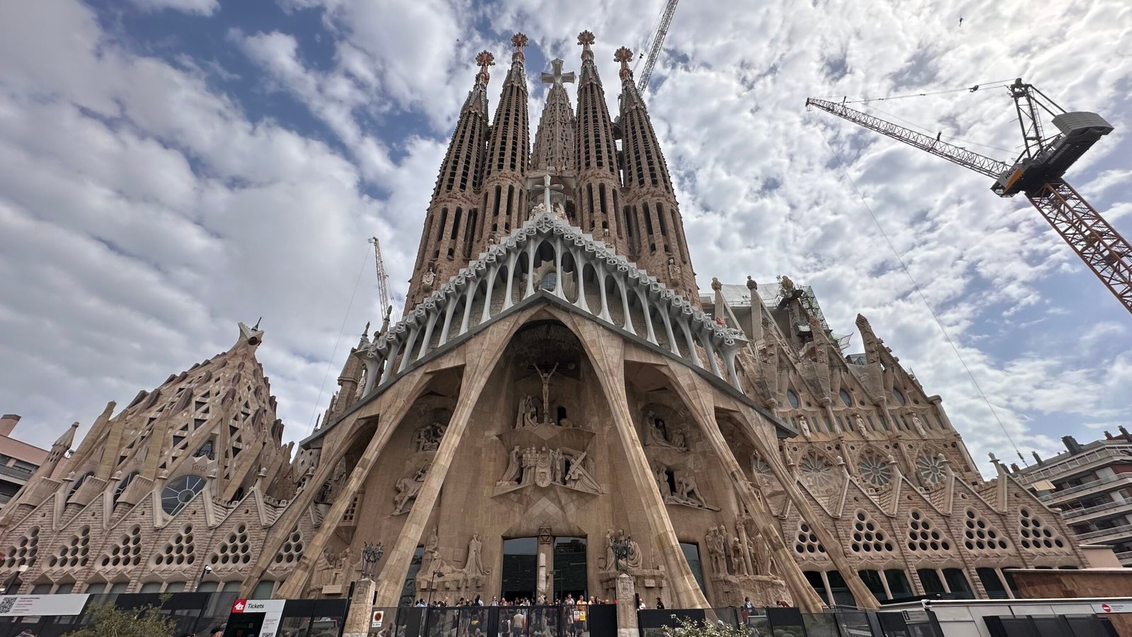 The Passion facade and towers of the Sagrada Família rising under a cloudy Barcelona sky