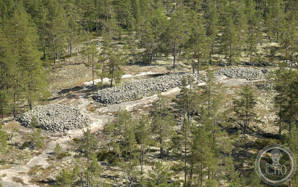 Low Bronze Age stone burial cairns spread across a rocky, pine-clad slope at Sammallahdenmäki, Finland