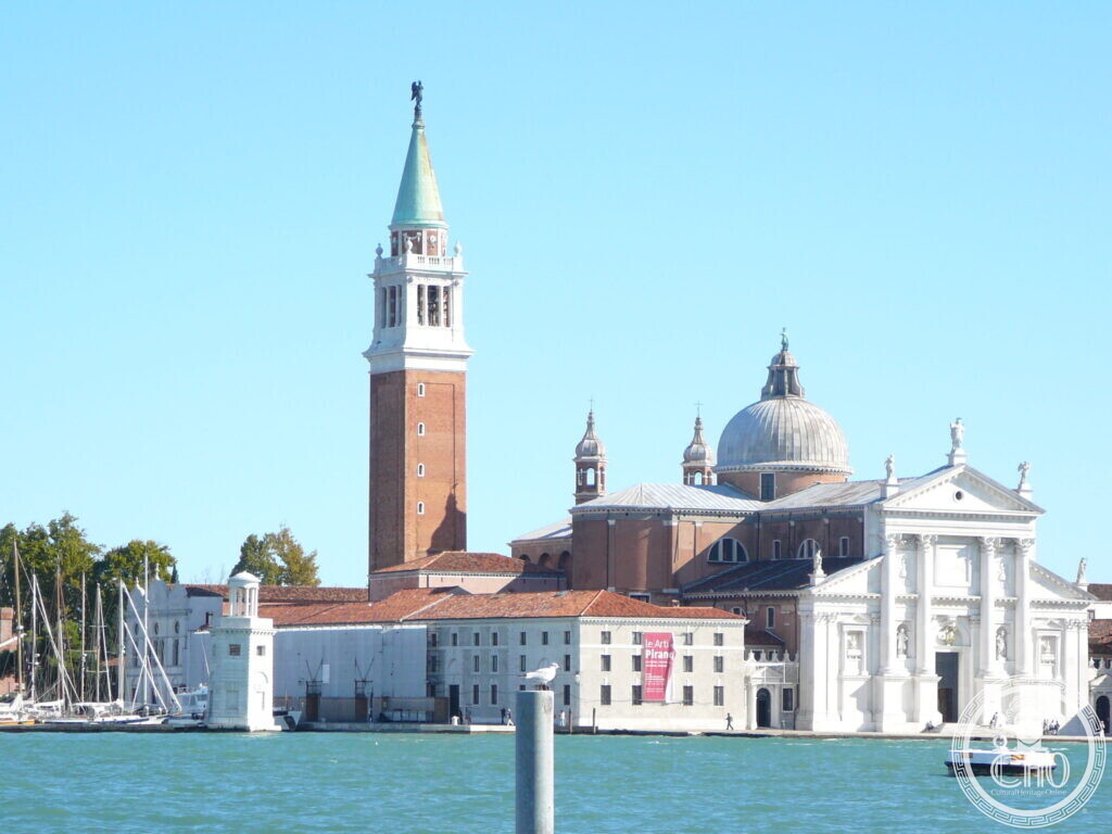 The white classical facade of the basilica of San Giorgio Maggiore with its dome and tall brick campanile, seen across the lagoon