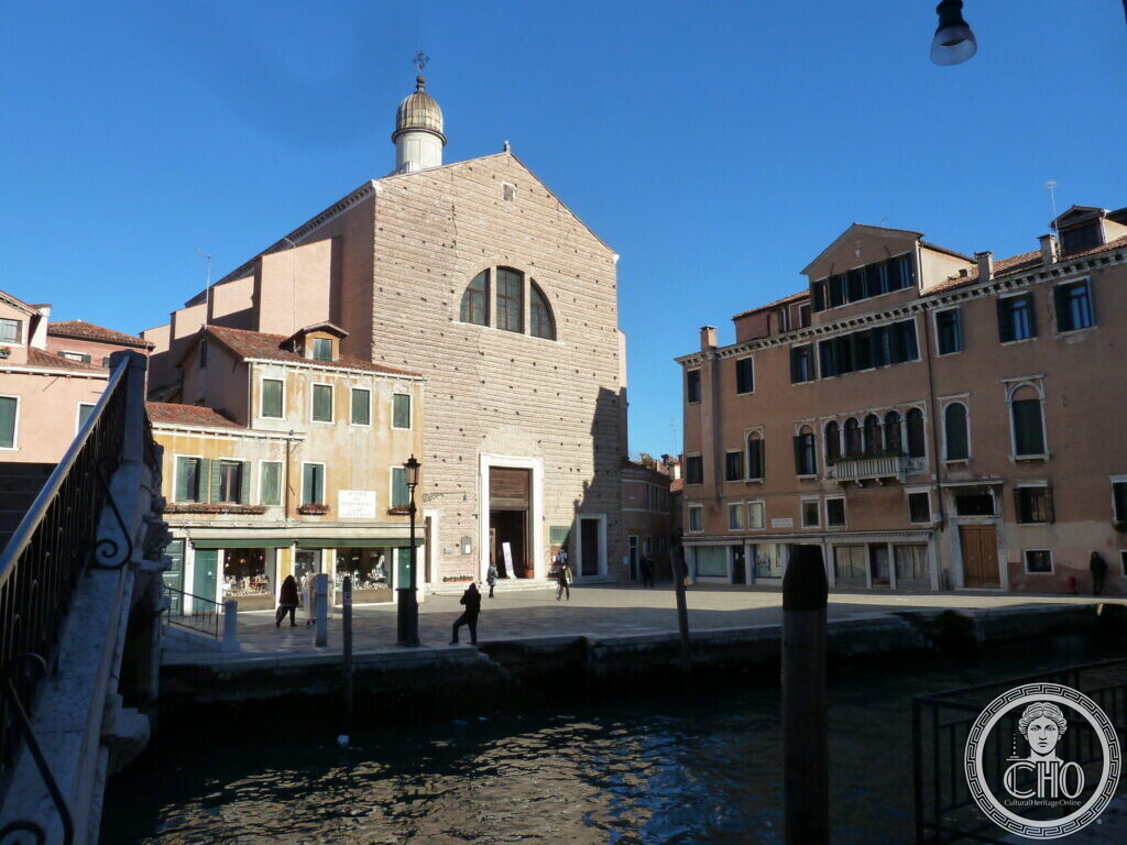 The brick front of San Pantalon with its small dome, seen across a canal from a bridge, houses on both sides of the campo