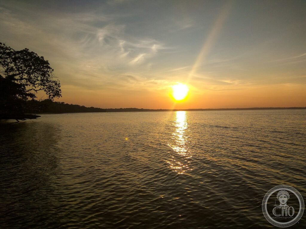 A calm sea and forested shore at sunset in Ujung Kulon National Park, western Java