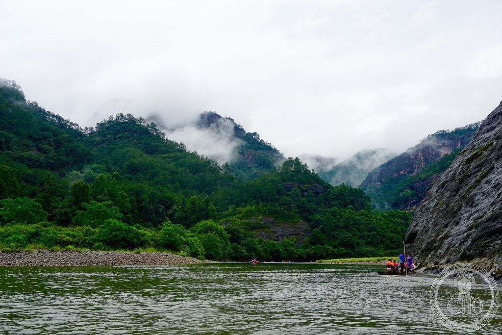 Misty cliffs above the Nine-Bend River winding through Mount Wuyi, with a bamboo raft