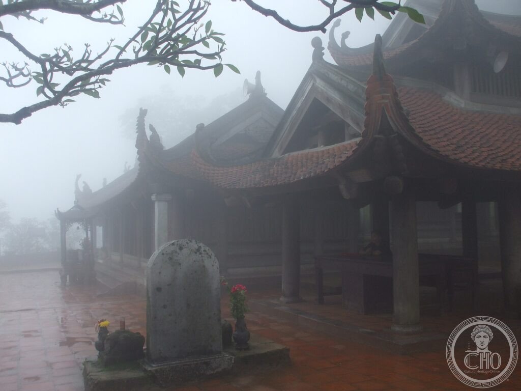 A mist-shrouded traditional Vietnamese pagoda with curved tiled roofs on the mountain of Yen Tu
