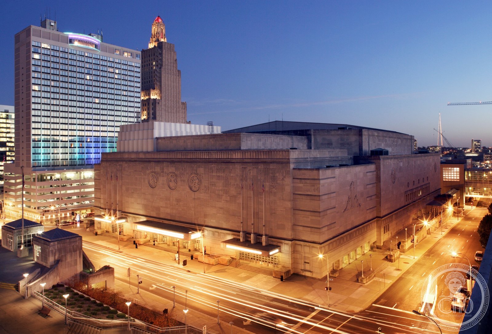 The Art Deco facade of Kansas City Municipal Auditorium at night, its limestone exterior illuminated against the Missouri sky