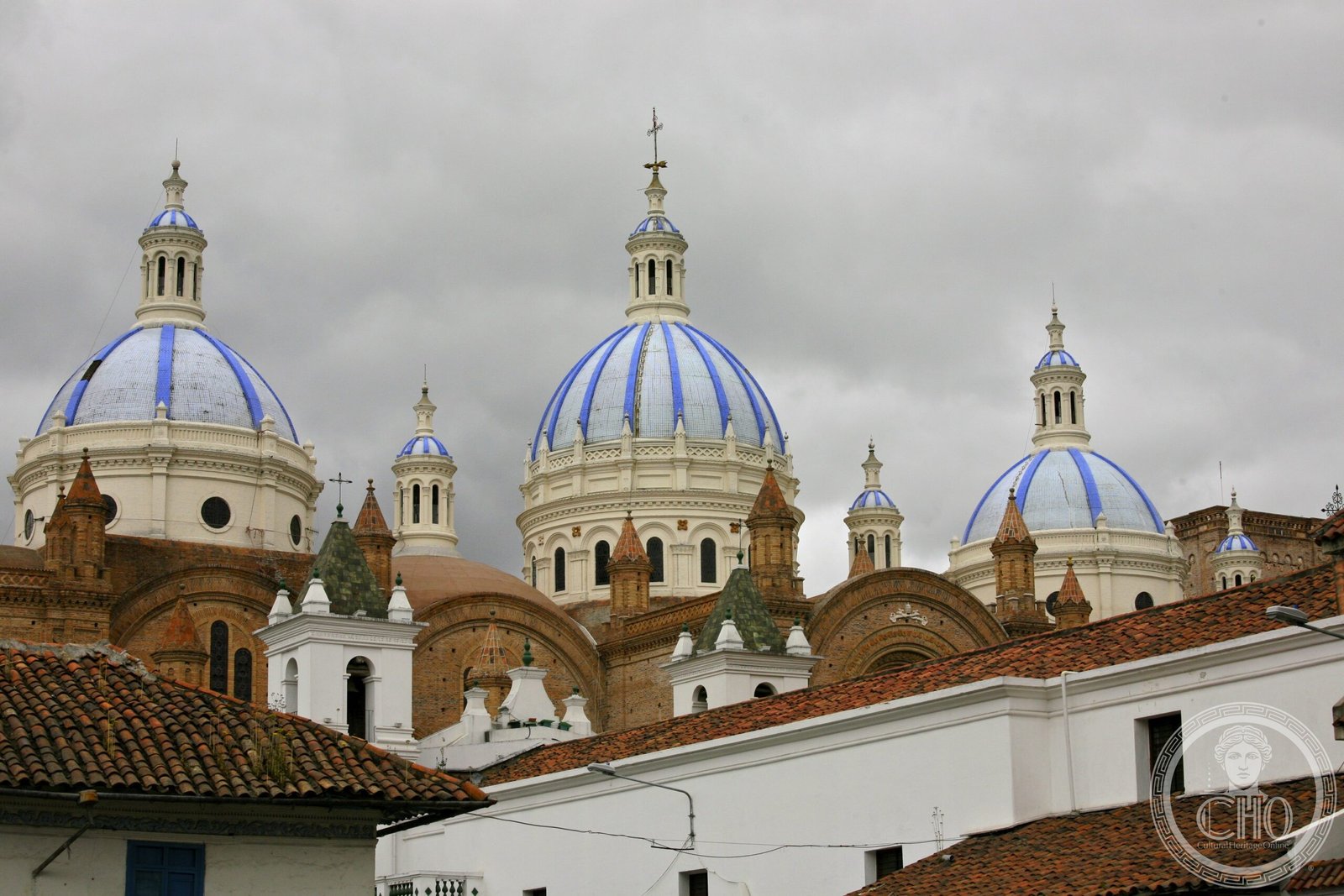 Blue and white glazed tile domes of the New Cathedral of Cuenca, Ecuador, seen from above the city's terracotta rooftops