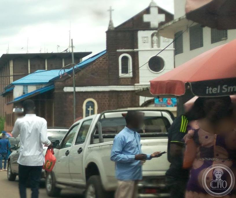 Sacred Heart Cathedral in Freetown, Sierra Leone, a dark brick Gothic Revival facade with white stone trim, a rose window and a large white cross